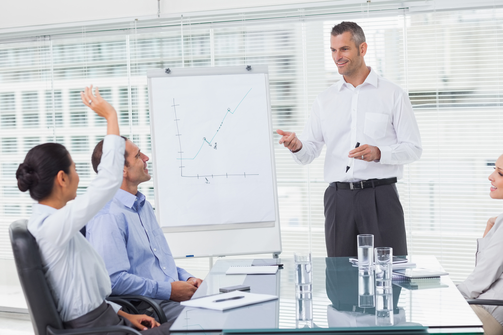 Businesswoman asking question during her colleagues presentation in bright office-1